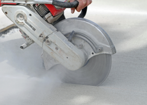 A close up of a saw cutting into concrete